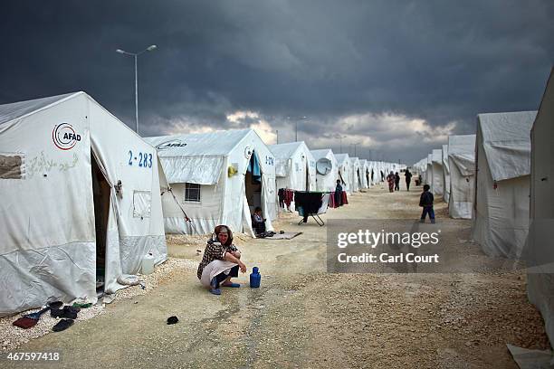 Syrian woman squats near her tent in Suruc refugee camp on March 25, 2015 in Suruc, Turkey. The camp is the largest of its kind in Turkey with a...