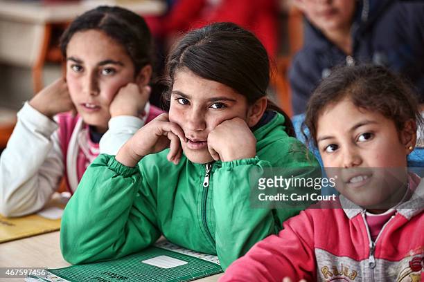 Syrian children listen to a teacher during a lesson in a temporary classroom in Suruc refugee camp on March 25, 2015 in Suruc, Turkey. The camp is...