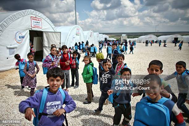 Syrian children react to the camera as they wait to attend lessons at a school in Suruc refugee camp on March 25, 2015 in Suruc, Turkey. The camp is...