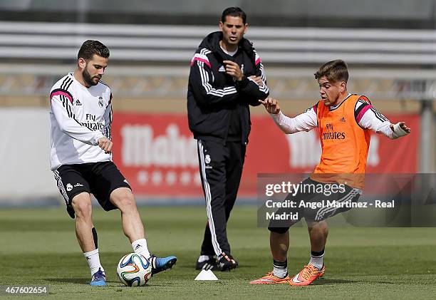 Nacho Fernandez of Real Madrid competes for the ball with Alvaro Jimenez of Real Madrid Academy as assistant coach Fernando Hierro gives instructions...