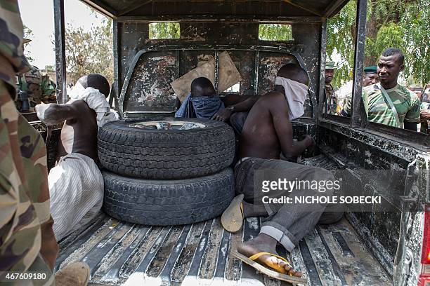 Three young men, who were discovered while entering Bama, sit blindfolded in the back of a pick-up truck before being taken for interrogation by the...