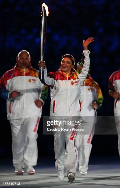 Alina Kabaeva carries the Olympic torch into the stadium during the Opening Ceremony of the Sochi 2014 Winter Olympics at Fisht Olympic Stadium on...