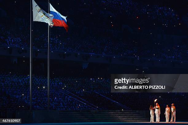 Russian Olympic medalist Alexander Karelin gives the Olympic flame to Russian Olympic medalist Alina Kabayeva during the Opening Ceremony of the...