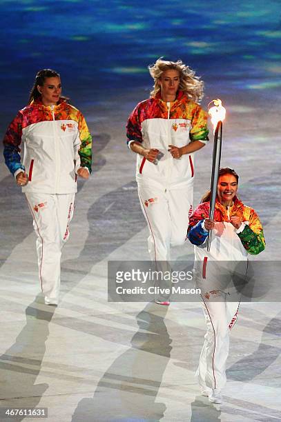 Olympic torch bearer Alina Kabaeva carries the torch with Maria Sharapova and Elena Isinbaeva during the Opening Ceremony of the Sochi 2014 Winter...