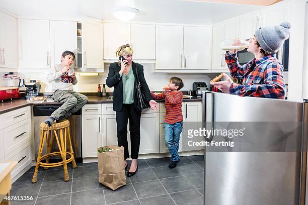 mother just arrived home from work and already multi-tasking. - crowded kitchen stock pictures, royalty-free photos & images