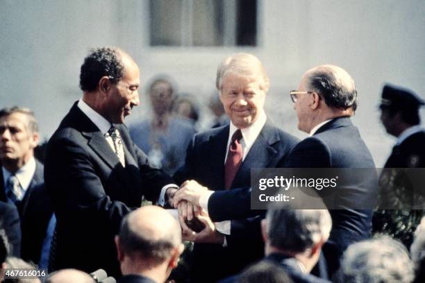 President Jimmy Carter congratulates Egyptian President Anwar al-Sadat and Israeli Premier Menachem Begin in three-way handshake on March 26, 1979 on...