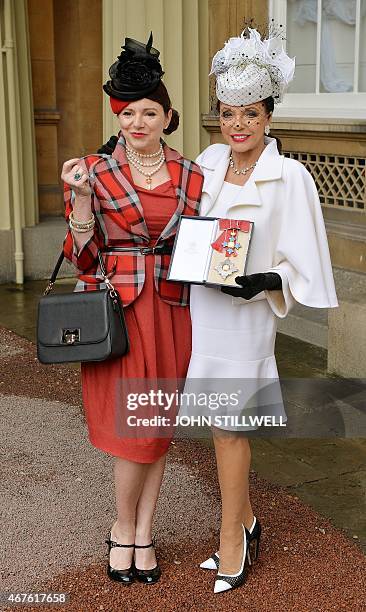 British actress Joan Collins poses for pictures with her daughter Tara Newley as she holds her insignia of Commander of the Order of the British...