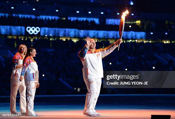 Russian former wrestler Alexander Karelin holds up the Olympic torch during the Opening Ceremony of the Sochi Winter Olympics at the Fisht Olympic...