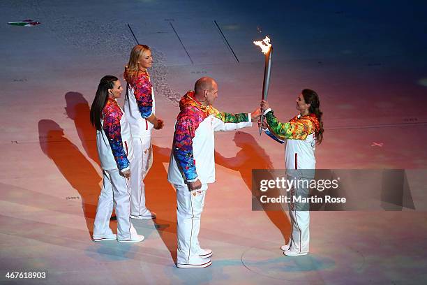 Alexandr Karelin hands the Olympic torch to Alina Kabaeva as Elena Isinbaeva and Maria Sharapova look on during the Opening Ceremony of the Sochi...