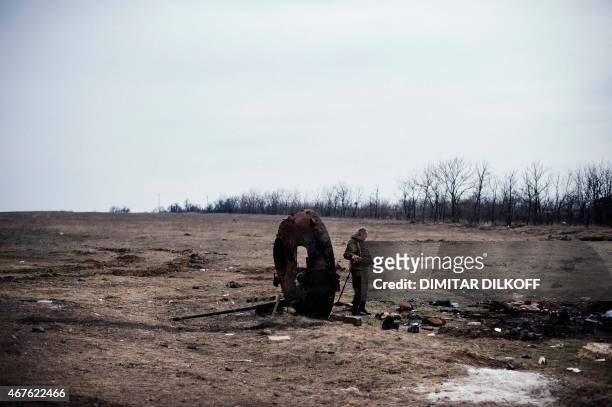 Pro-Russian rebel looks at parts of a destroyed APC near the village of Lohvynove near the eastern Ukrainian town of Debaltseve on March 26, 2015....