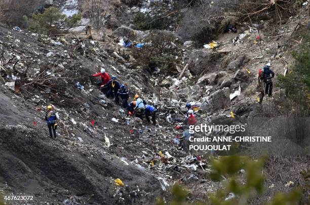 Investigators work on March 26, 2015 near scattered debris while making their way through the crash site of the Germanwings Airbus A320 that crashed...