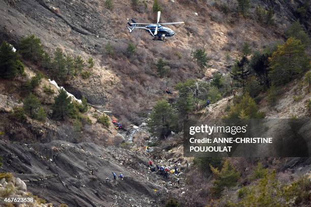 Helicopter carries investigators on March 26, 2015 near scattered debris on the crash site of the Germanwings Airbus A320 that crashed in the French...