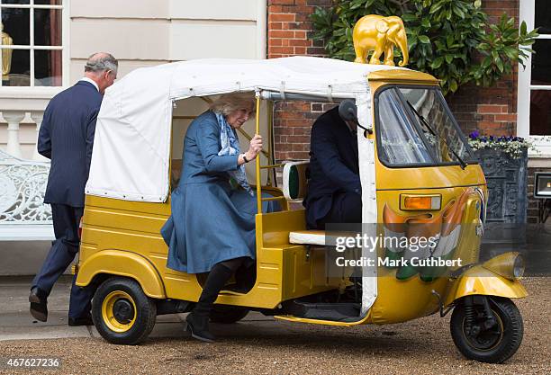 Camilla, Duchess of Cornwall and Prince Charles, Prince of Wales ride in a rickshaw at Clarence House on March 26, 2015 in London, England.