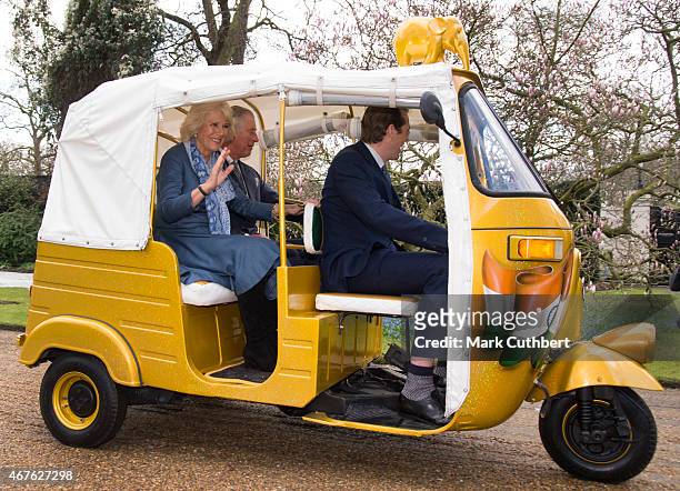 Camilla, Duchess of Cornwall and Prince Charles, Prince of Wales ride in a rickshaw at Clarence House on March 26, 2015 in London, England.