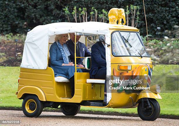 Camilla, Duchess of Cornwall and Prince Charles, Prince of Wales ride in a rickshaw at Clarence House on March 26, 2015 in London, England.