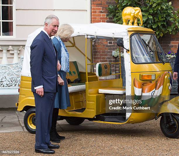 Camilla, Duchess of Cornwall and Prince Charles, Prince of Wales ride in a rickshaw at Clarence House on March 26, 2015 in London, England.