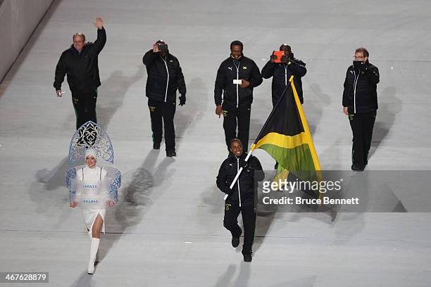 Bobsleigh racer Marvin Dixon of the Jamaica Olympic team carries his country's flag during the Opening Ceremony of the Sochi 2014 Winter Olympics at...