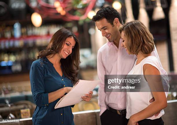 restaurant hostess welcoming customers - hostess stock pictures, royalty-free photos & images