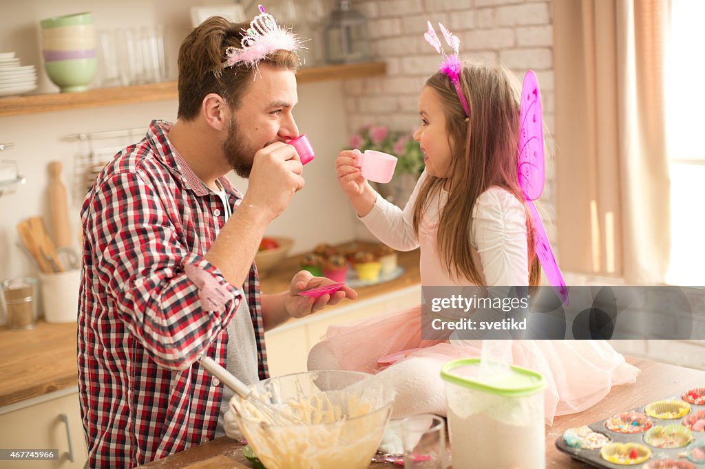 Father and daughter baking and having tea party in kitchen.