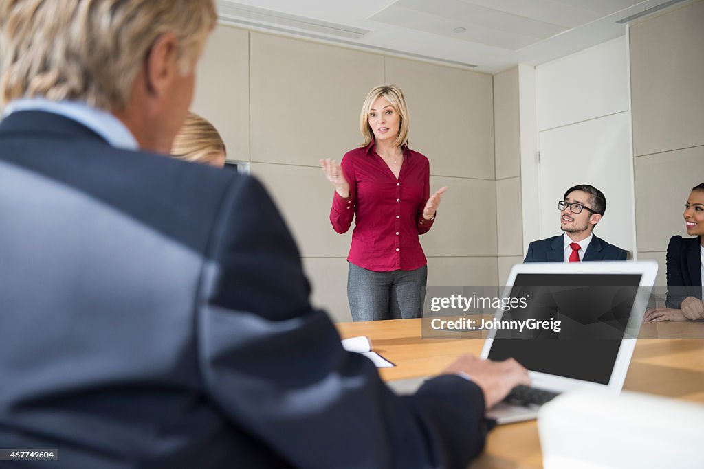 Businesswoman Giving Presentation To Colleagues At Conference Table