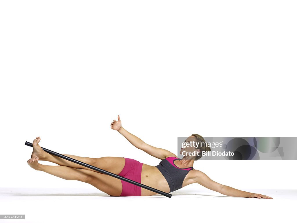 Woman doing side rise abs with pole in studio