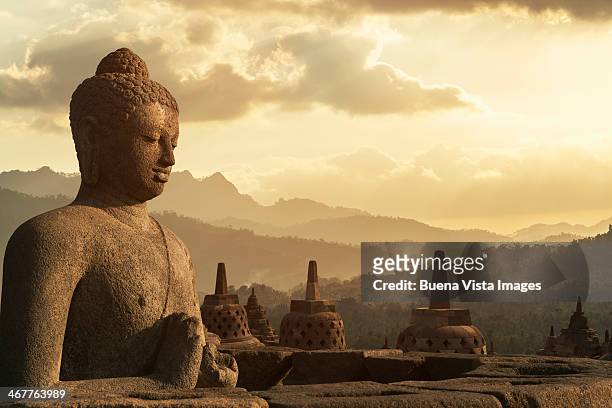 sunset over buddha statue in borobudur. - borobudur stock-fotos und bilder