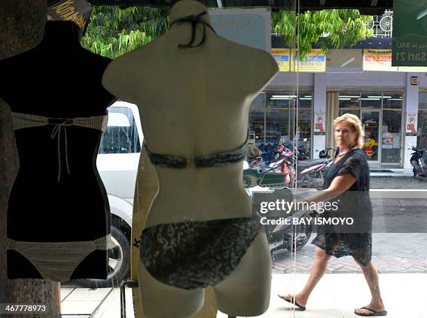 Foreign tourist walks past Australian drug trafficker Schapelle Corby's sister, Mercedes Corby, surfing and bikini shop, in Kuta, on February 8,...