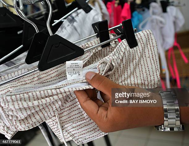 An employee of Australian drug trafficker Schapelle Corby's sister, Mercedes Corby, surfing and bikini shop, shows the tag of the merchandise which...