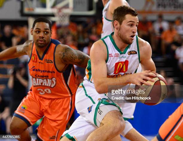 Mitch Norton of the Crocodiles drives past Demetri McCamey of the Taipans during the round 17 NBL match between the Cairns Taipans and the Townsville...