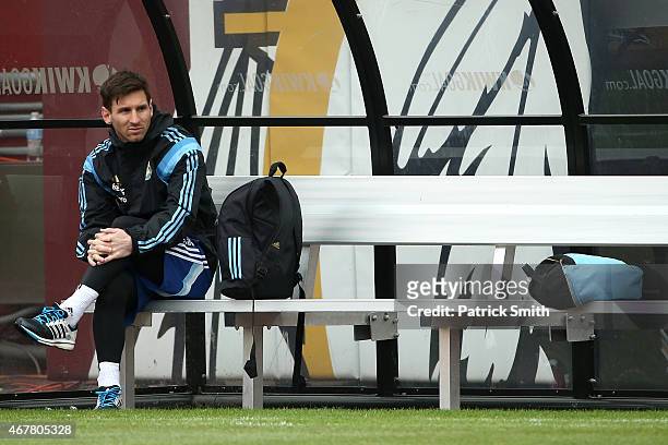Lionel Messi of the Argentinian national soccer team sits on the bench as his teammates practice on the field in preparation to take on El Salvador...