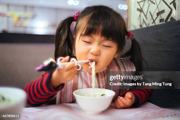 Toddler girl having noodles in restaurant