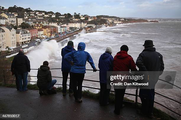 People gather on the cliffs to watch waves crash over the main Exeter to Plymouth railway line that has been closed due to parts of it being washed...