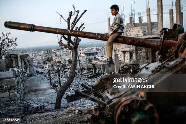 Syrian Kurdish boy sits on a destroyed tank in the Syrian town of Kobane, also known as Ain al-Arab, on March 27, 2015. Islamic State fighters were...