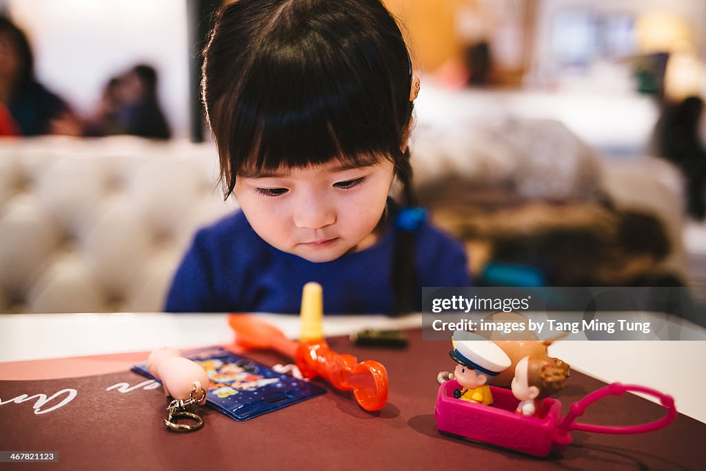 Toddler girl playing toys in the restaurant