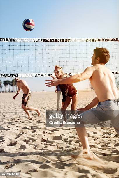 menschen spielen sie beach-volleyball - beachvolleyball stock-fotos und bilder