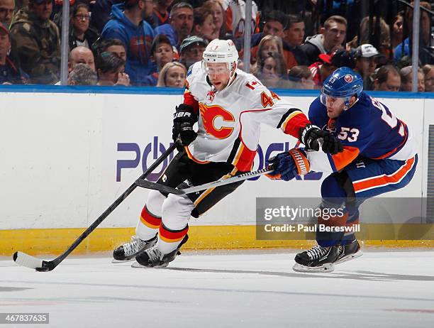 Casey Cizikas of the New York Islanders is held off by Chris Butler of the Calgary Flames in an NHL hockey game at Nassau Veterans Memorial Coliseum...