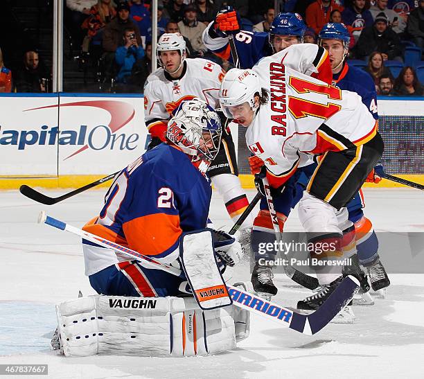 Goalie Evgeni Nabokov of the New York Islanders stops a shot by Mikael Backlund of the Calgary Flames during an NHL hockey game at Nassau Veterans...