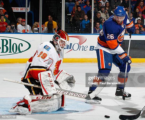 Thomas Vanek of the New York Islanders waits for a rebound as goalie Reto Berra of the Calgary Flames makes a save during an NHL hockey game at...