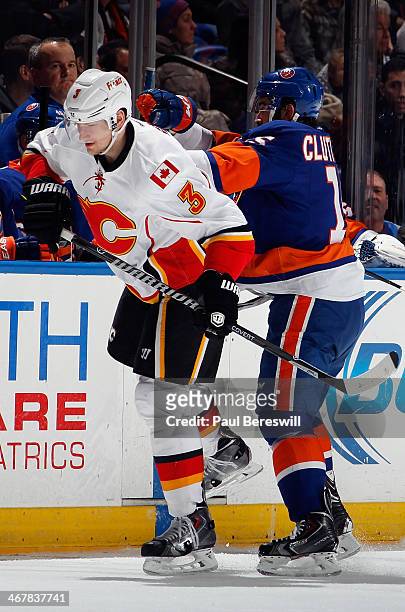 Ladislav Smid of the Calgary Flames is shoved by Cal Clutterbuck of the New York Islanders during an NHL hockey game at Nassau Veterans Memorial...