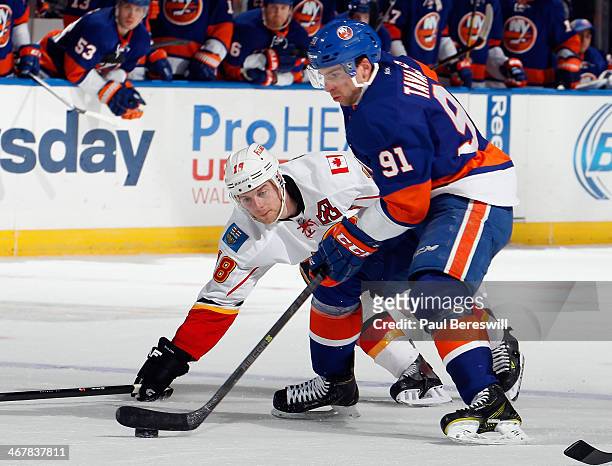 John Tavares of the New York Islanders skates past Matt Stajan of the Calgary Flames during an NHL hockey game at Nassau Veterans Memorial Coliseum...