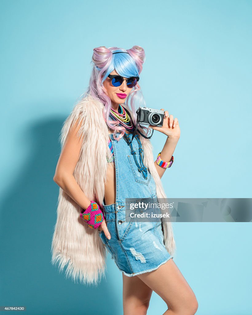 Pink hair girl in funky manga outfit holding camera