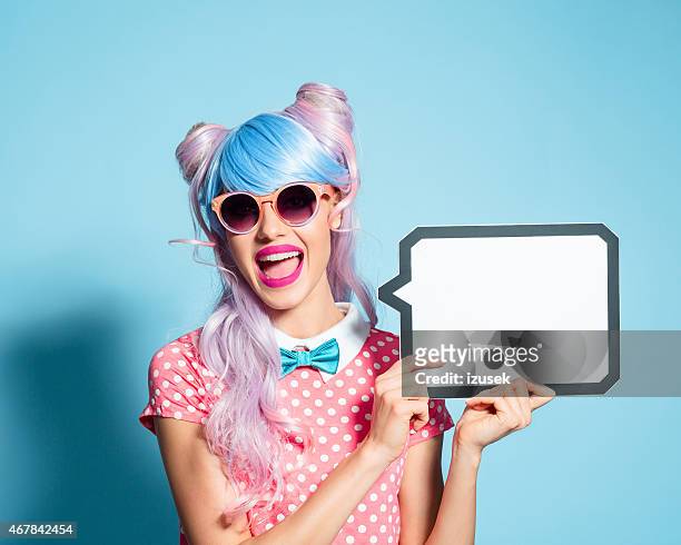happy pink hair manga style girl holding speech bubble - funky hair studio shot stock pictures, royalty-free photos & images
