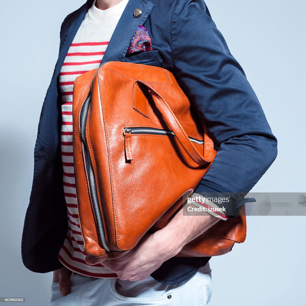 Fashionable man holding leather bag