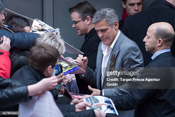 Matt Damon and George Clooney sign autographs as they leave the Berlinale Press Centre at Potsdamer Platz on February 8, 2014 in Berlin, Germany.