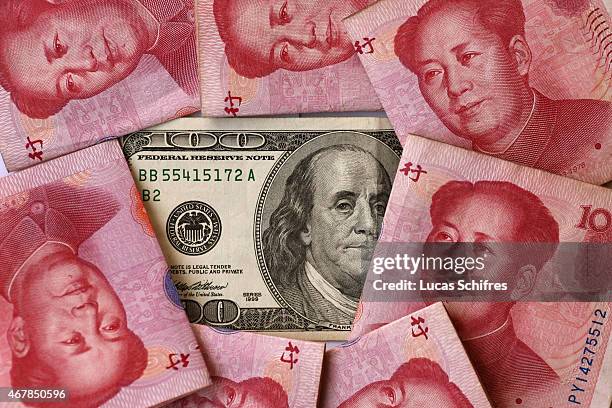 In this photo illustration, a one hundred U.S. Dollar banknote featuring Benjamin Franklin is on display by seven one hundred Chinese yuans banknotes...