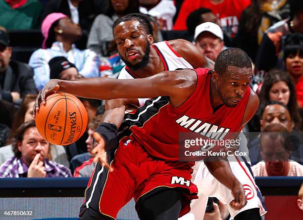 DeMarre Carroll of the Atlanta Hawks reaches for a steal against Luol Deng of the Miami Heat at Philips Arena on March 27, 2015 in Atlanta, Georgia....