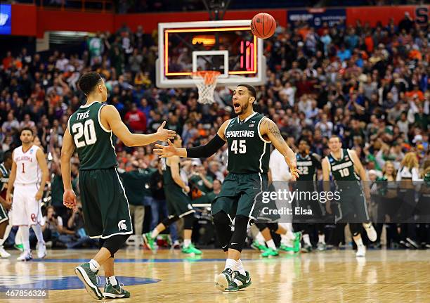 Denzel Valentine of the Michigan State Spartans celebrates with teammate Travis Trice after defeating the Oklahoma Sooners 62 to 58 during the East...