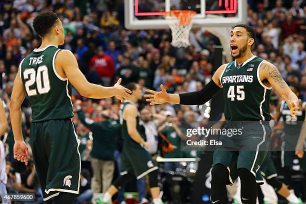 Denzel Valentine of the Michigan State Spartans celebrates with teammate Travis Trice after defeating the Oklahoma Sooners 62 to 58 during the East...