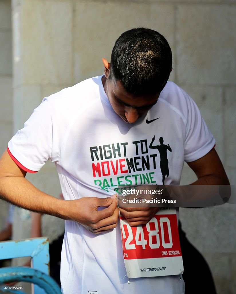 A Palestinian marathon runner adjusts his shirt before the...