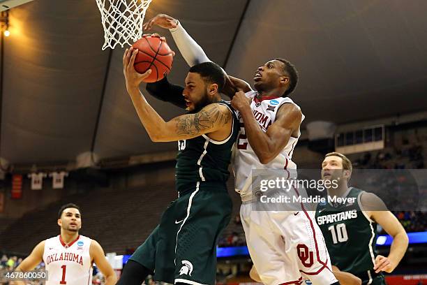 Buddy Hield of the Oklahoma Sooners fouls Denzel Valentine of the Michigan State Spartans late in the second half of the game during the East...
